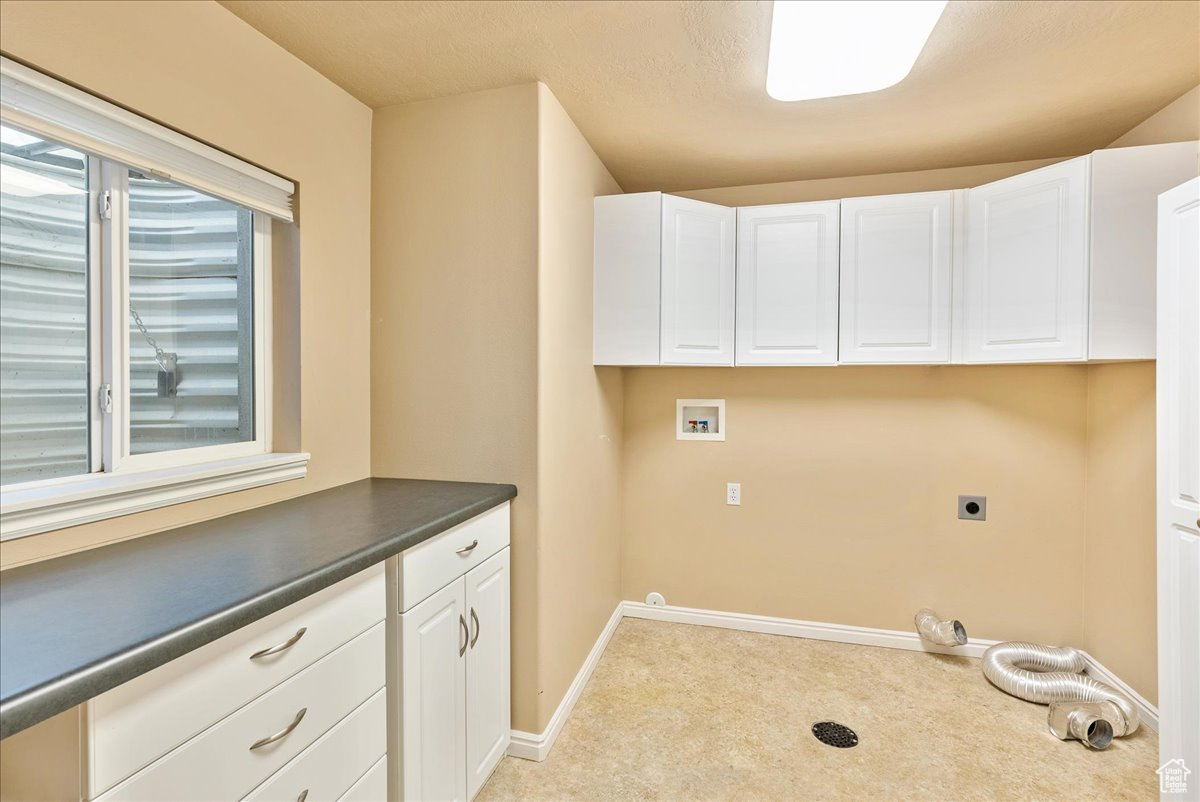 Laundry room with cabinets, hookup for a washing machine, light carpet, and electric dryer hookup