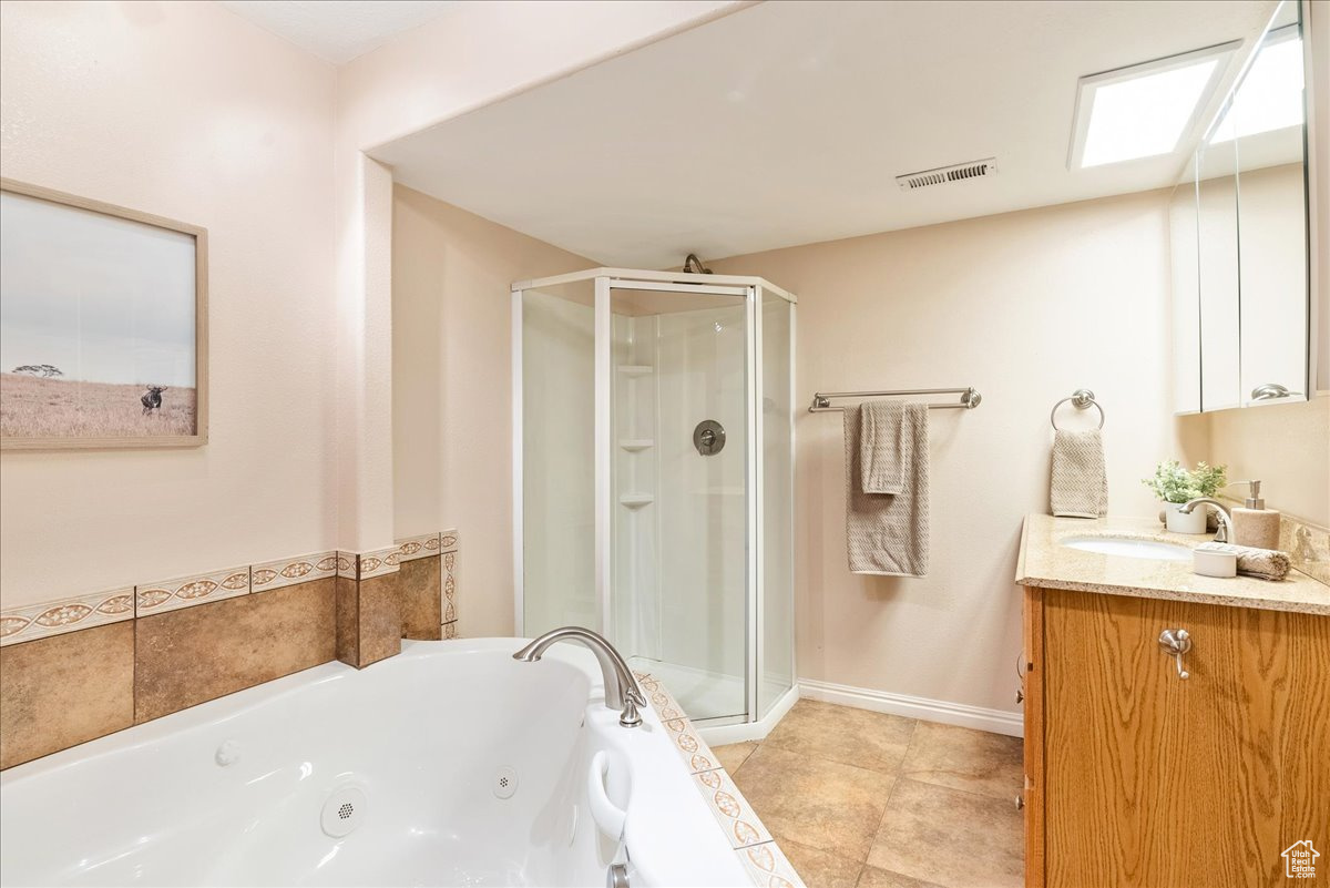 Bathroom featuring vanity, plus walk in shower, and tile patterned flooring