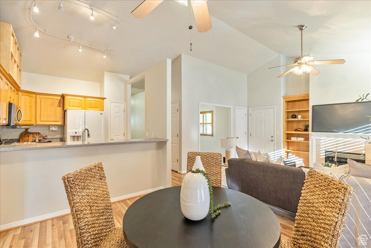 Dining room featuring light hardwood / wood-style floors, high vaulted ceiling, and ceiling fan