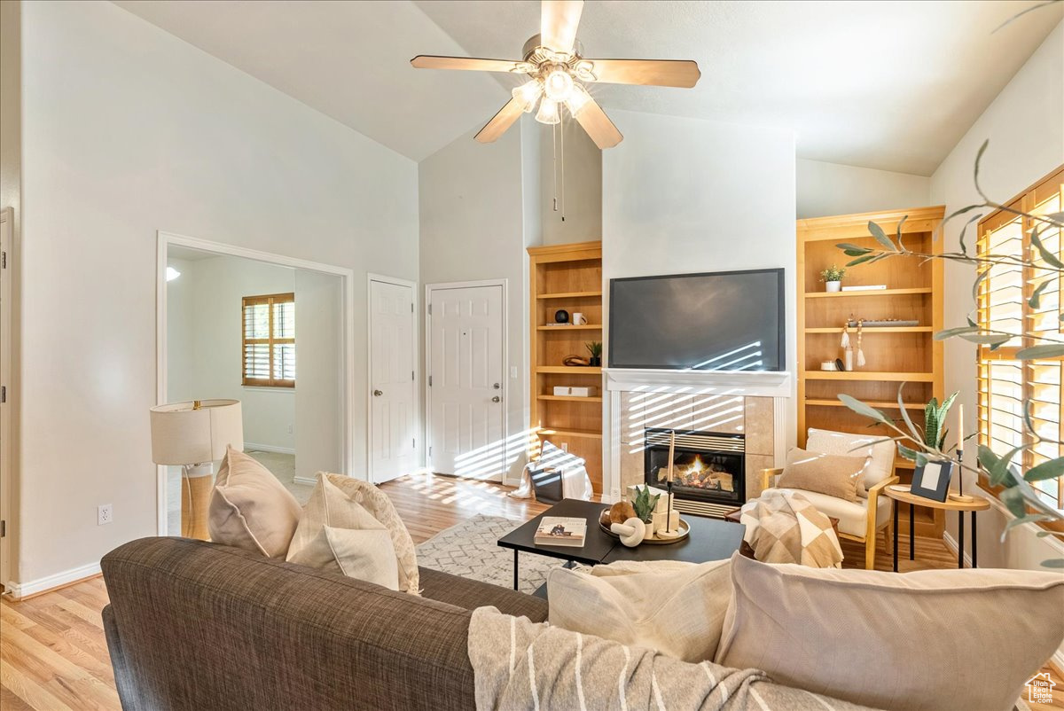 Living room featuring ceiling fan, lofted ceiling, light hardwood / wood-style flooring, and a tile fireplace