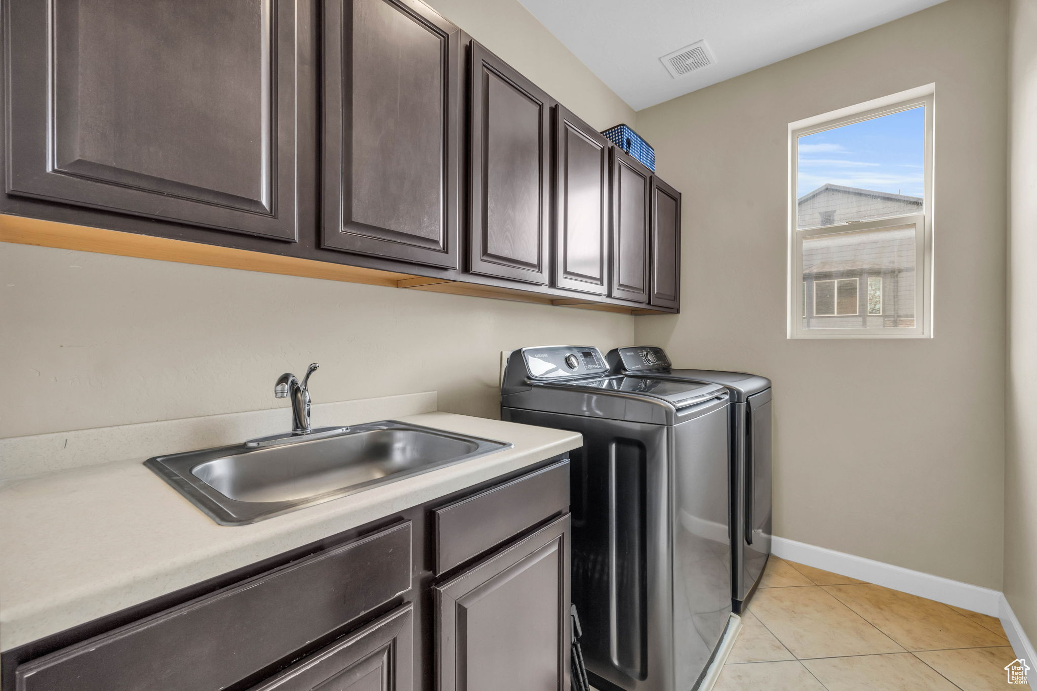 Washroom featuring cabinets, separate washer and dryer, sink, and light tile patterned floors