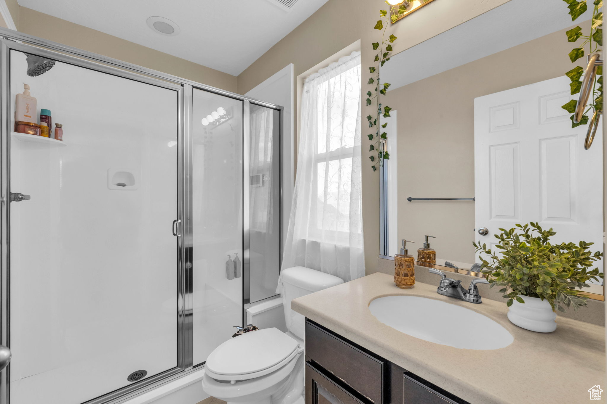 Bathroom featuring toilet, vanity, and walk in shower