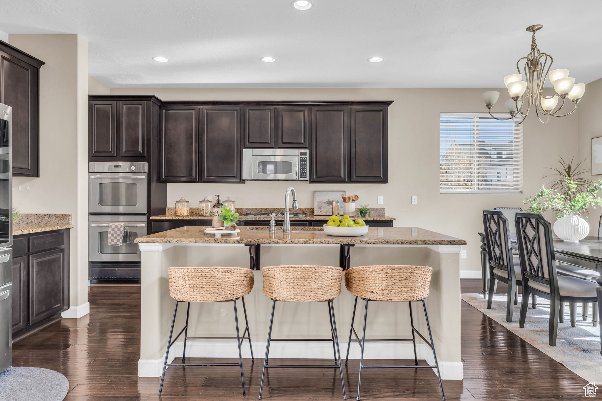 Kitchen featuring a kitchen island with sink, decorative light fixtures, dark hardwood / wood-style flooring, stainless steel appliances, and a chandelier