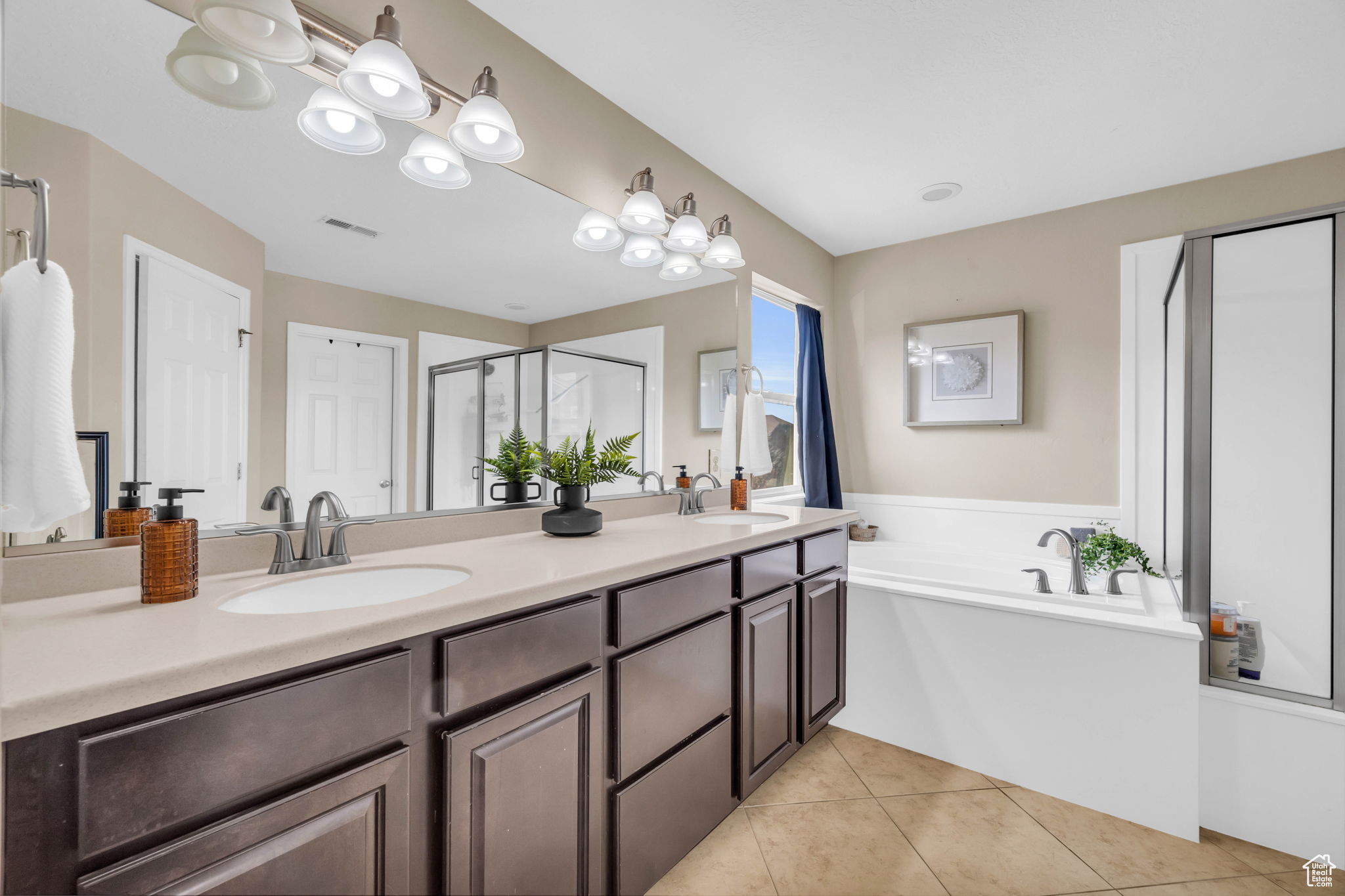 Bathroom featuring tile patterned floors, vanity, and plus walk in shower