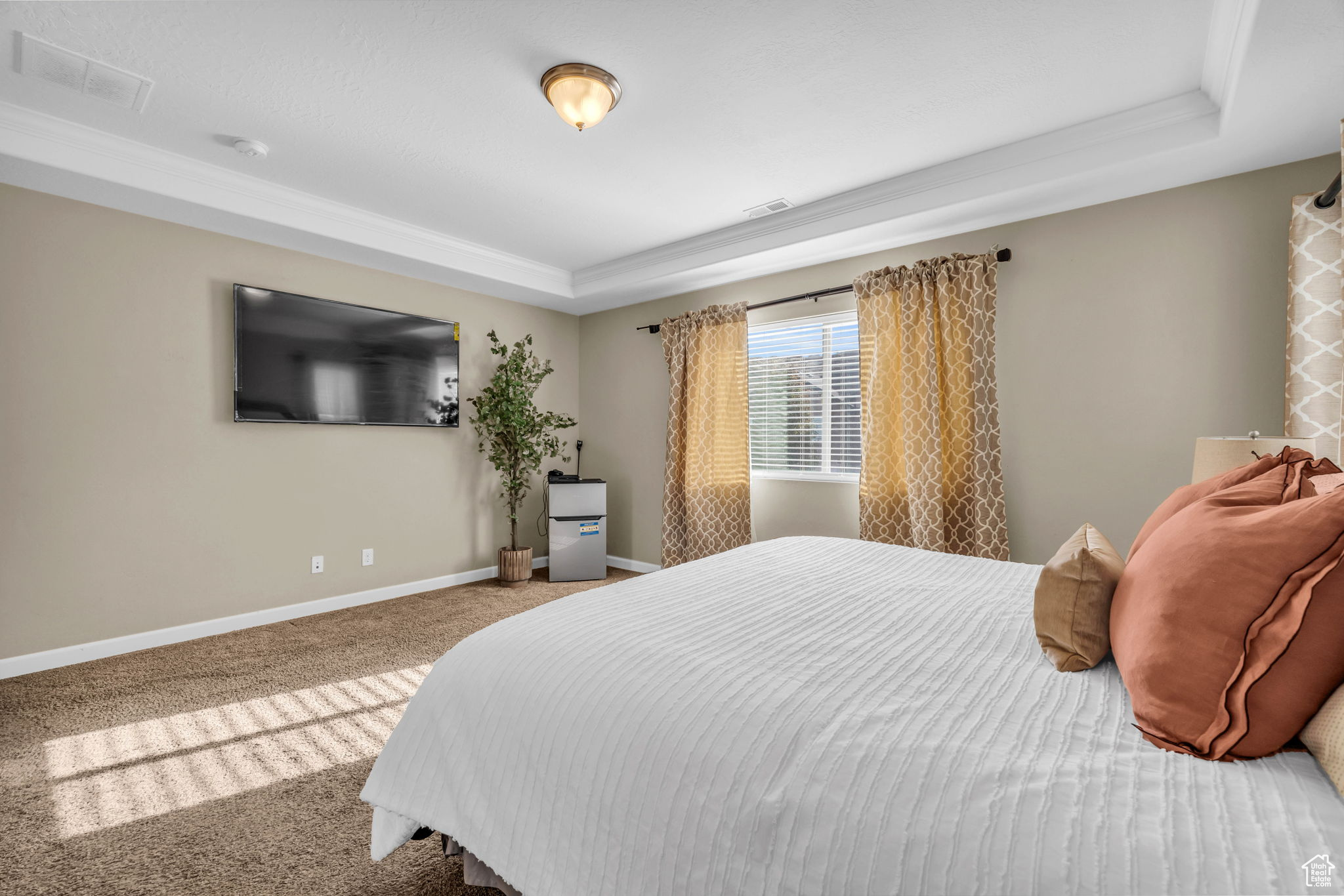 Bedroom featuring a raised ceiling, carpet floors, and ornamental molding