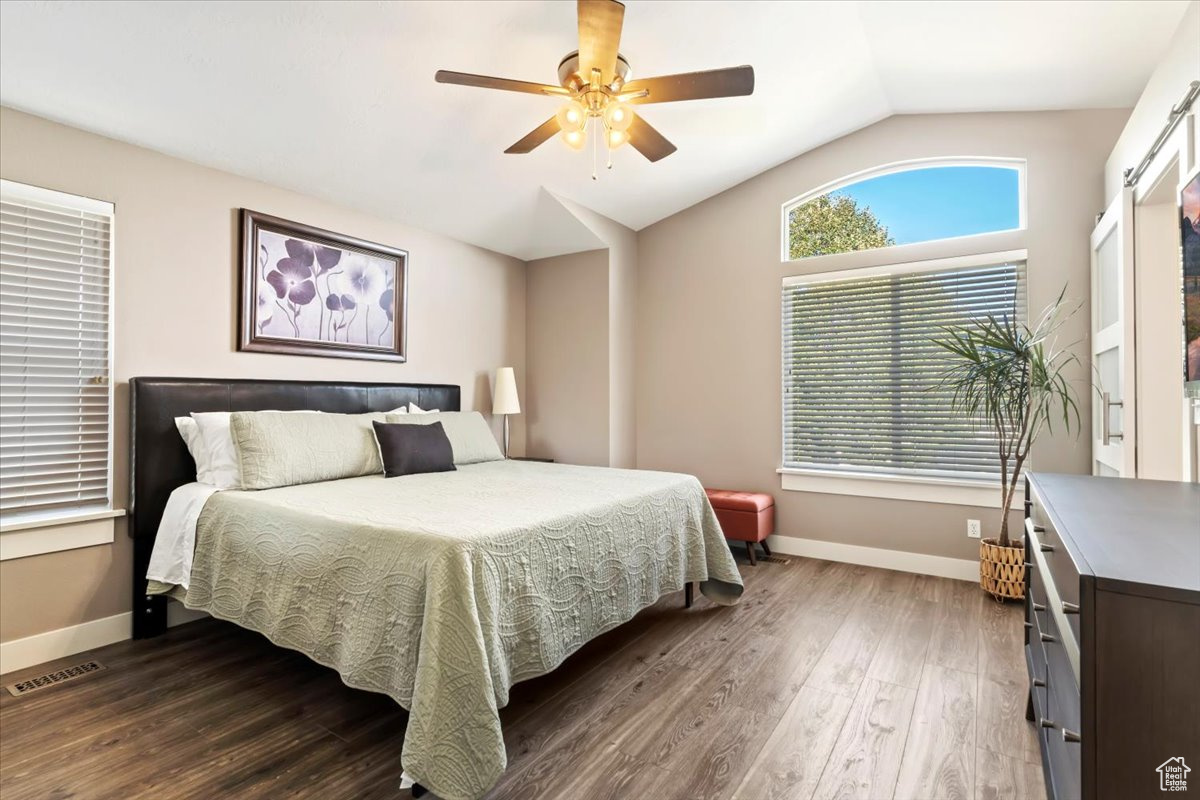 Bedroom with dark hardwood / wood-style flooring, lofted ceiling, and ceiling fan