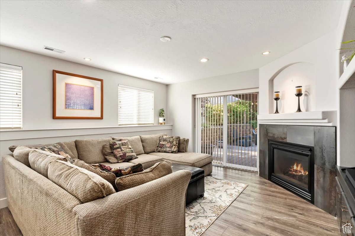 Living room with light hardwood / wood-style flooring, a tiled fireplace, and plenty of natural light