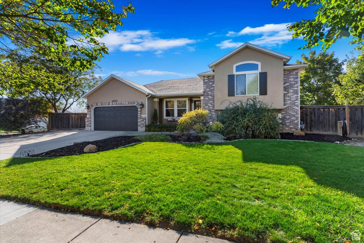 View of front facade featuring a front yard and a garage