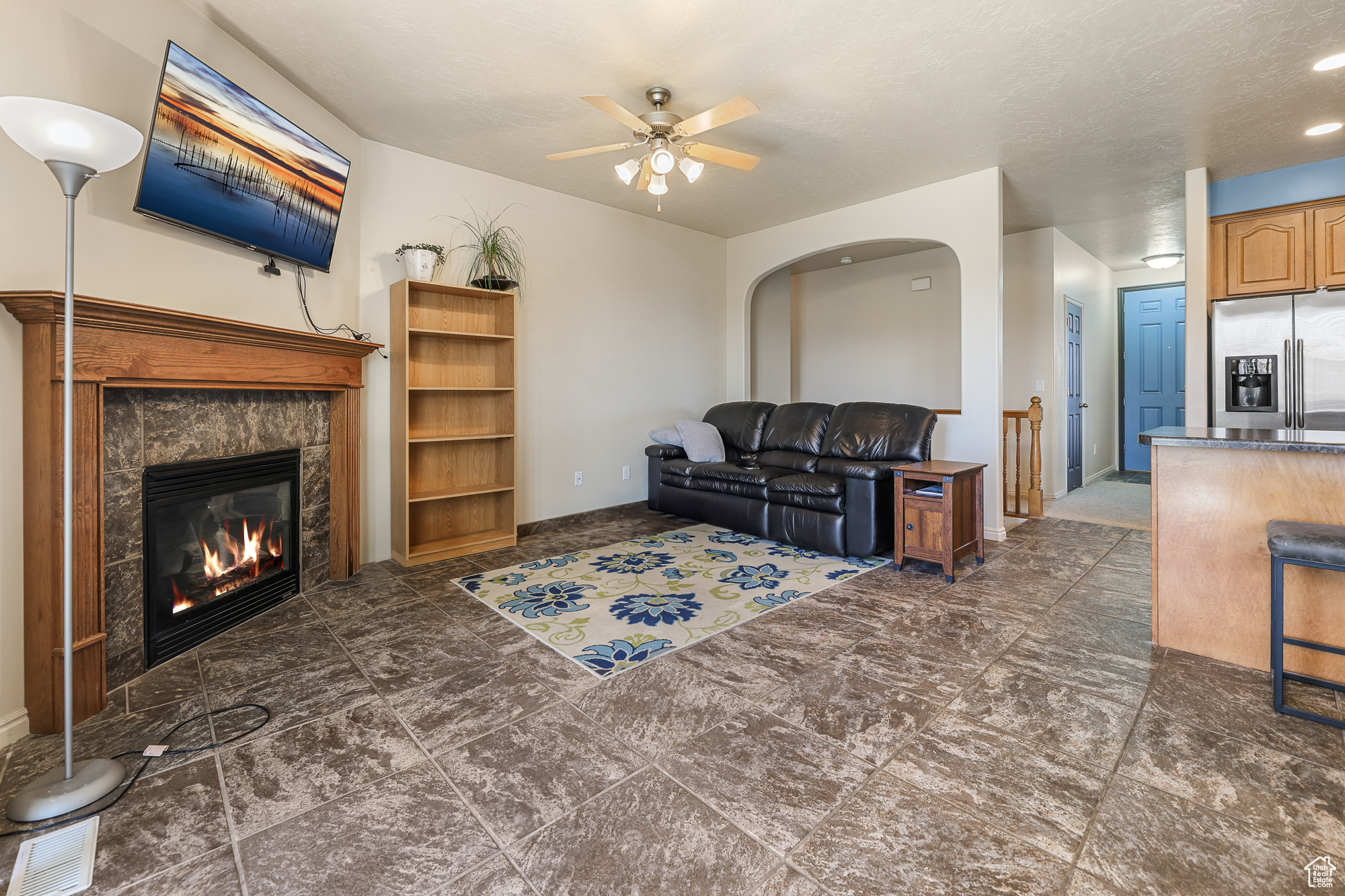 Living room with a textured ceiling, a fireplace, and ceiling fan