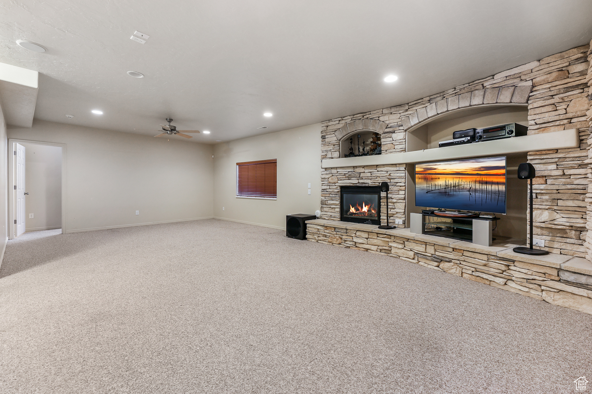 Unfurnished living room featuring a fireplace, carpet, and ceiling fan