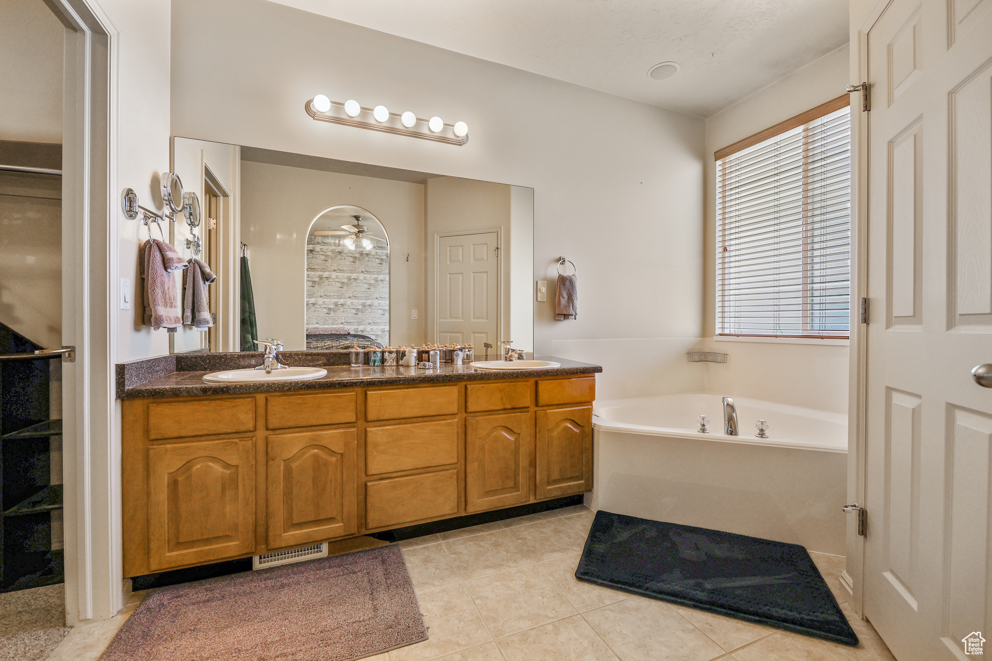 Bathroom with vanity, a tub to relax in, ceiling fan, and tile patterned flooring