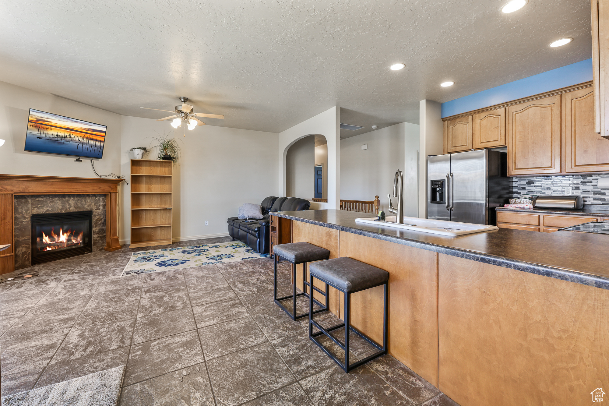 Kitchen with sink, stainless steel fridge with ice dispenser, a textured ceiling, and tasteful backsplash