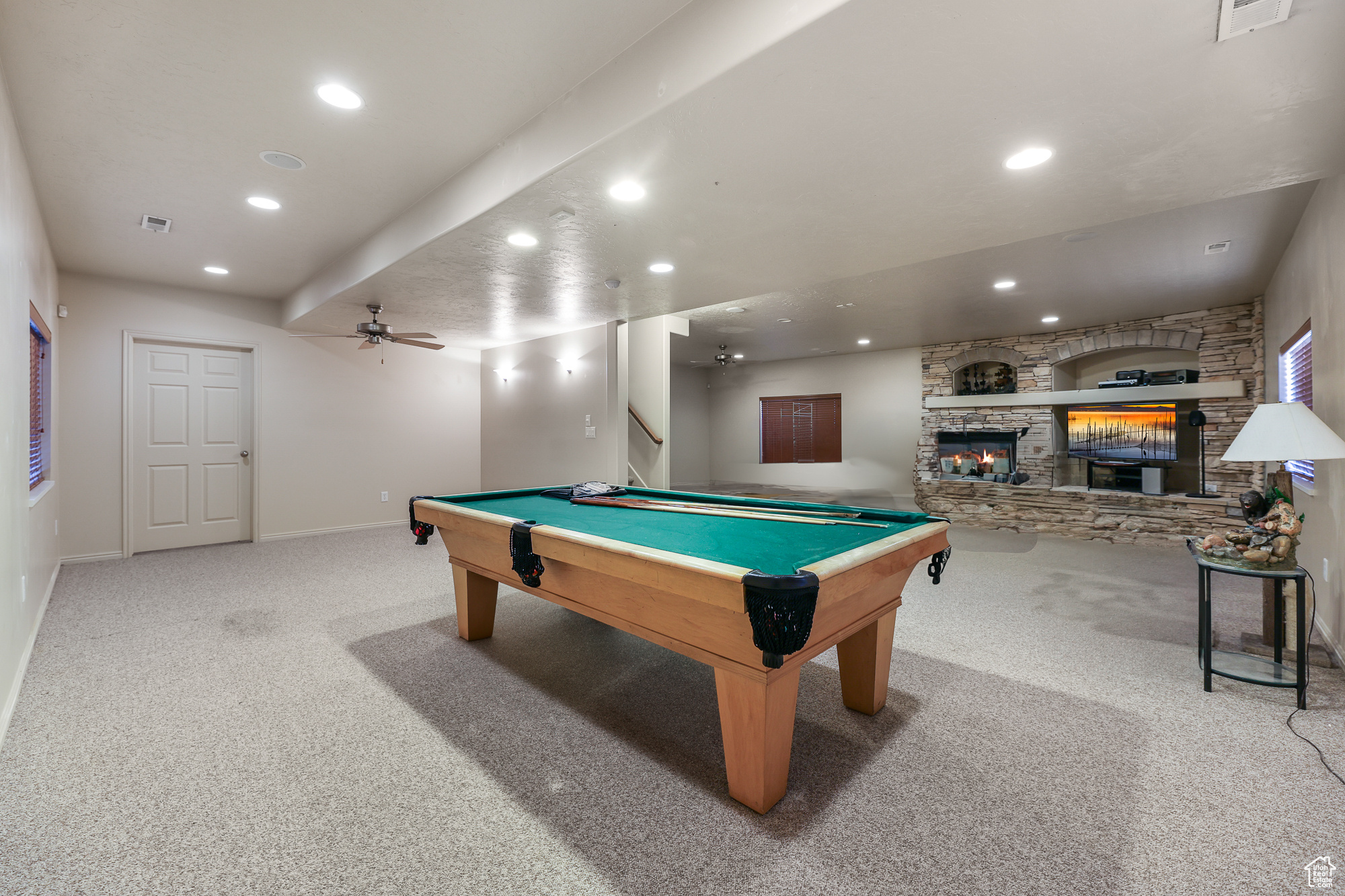 Recreation room with ceiling fan, a stone fireplace, billiards, and light colored carpet