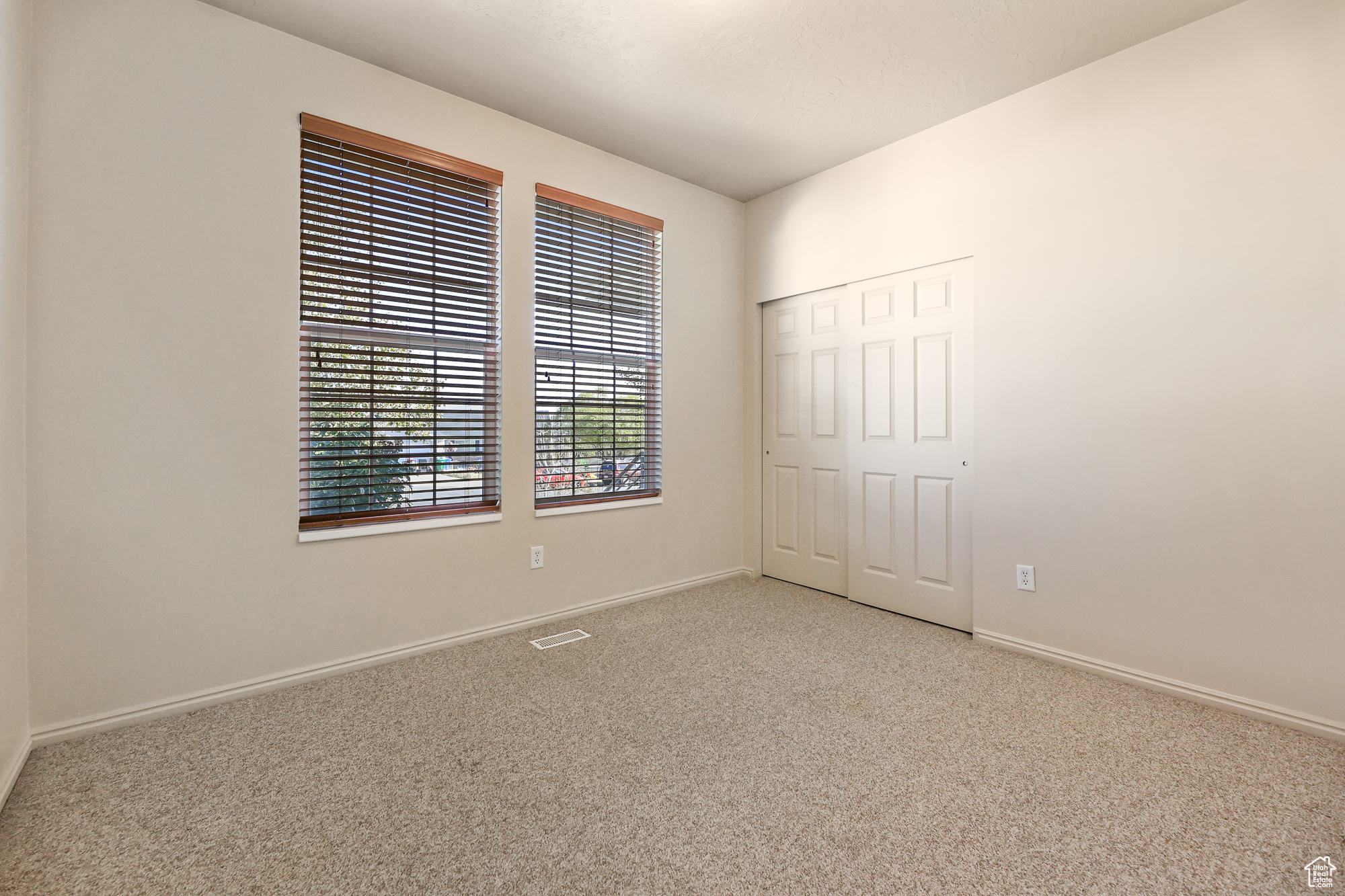 Unfurnished bedroom with light carpet and a closet