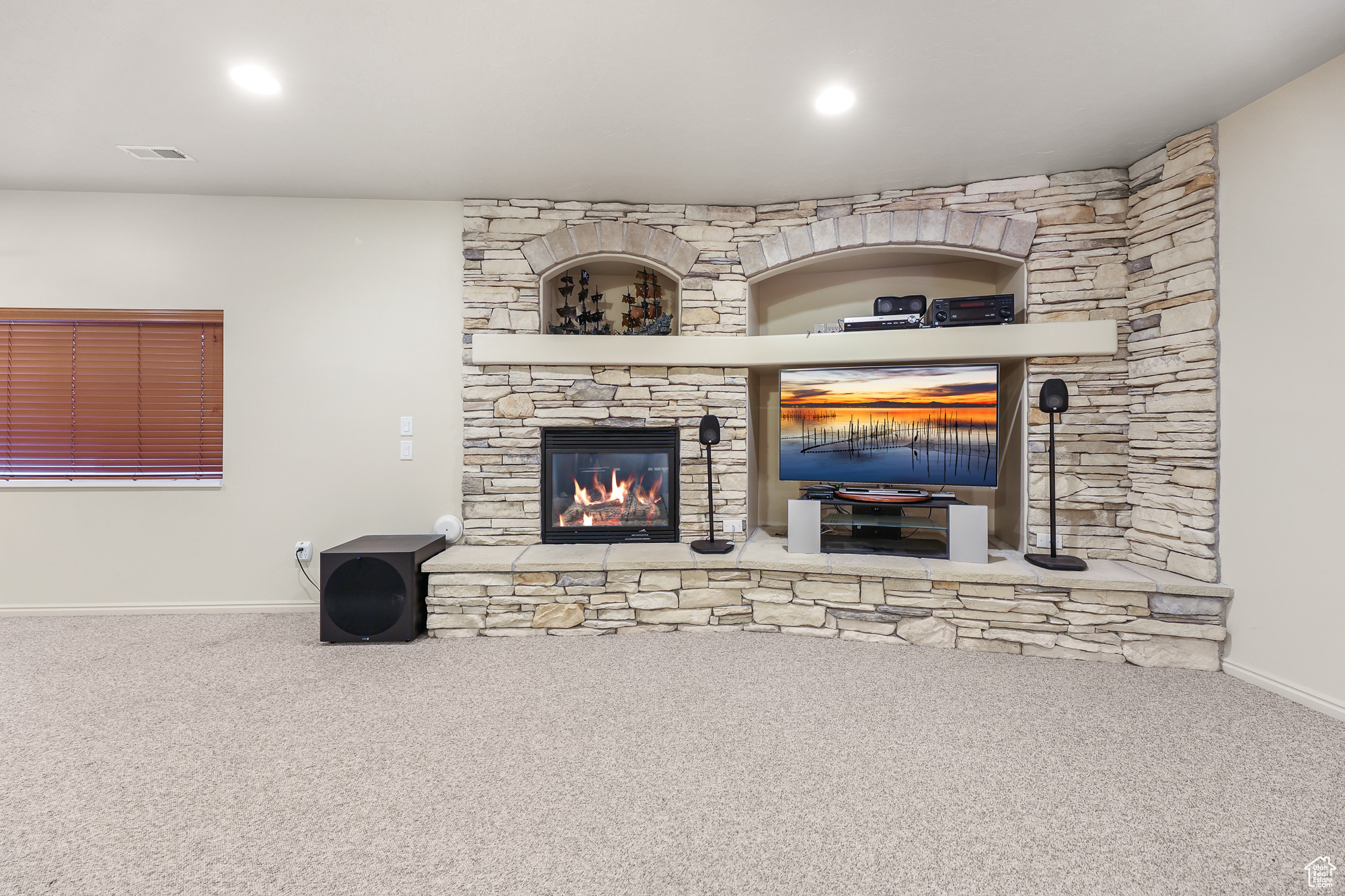 Living room with a stone fireplace and carpet flooring