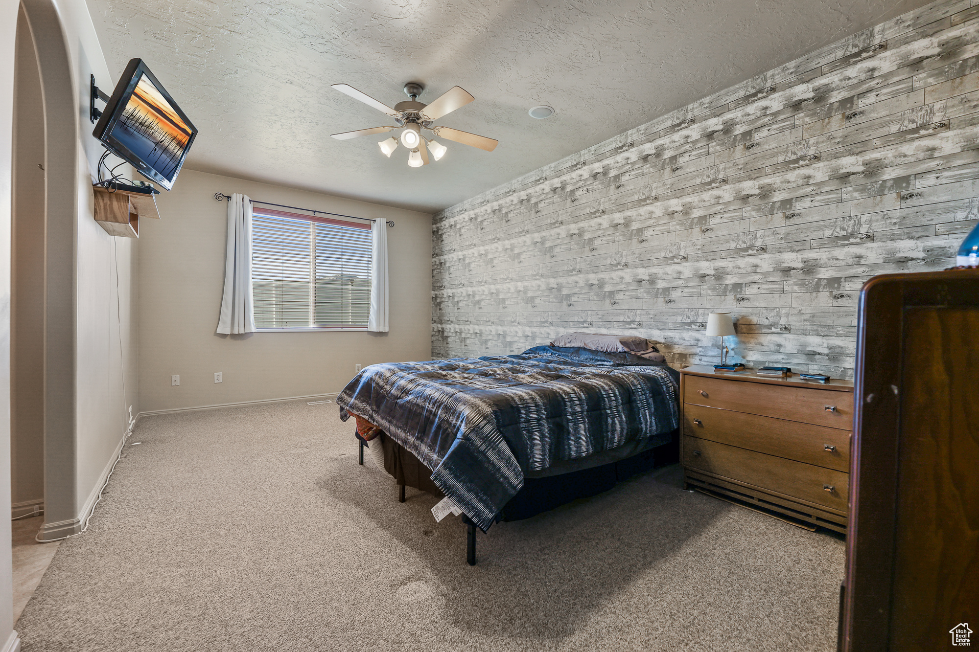 Bedroom with ceiling fan, a textured ceiling, and light colored carpet