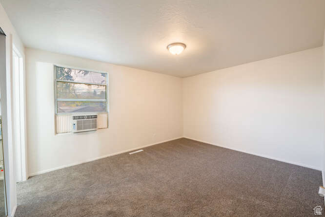 Primary bedroom with cooling unit and gray colored carpet