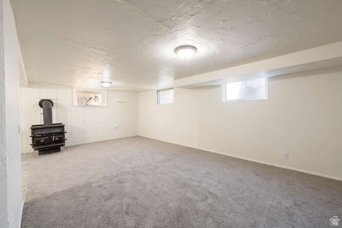 Basement with carpet and a wood stove