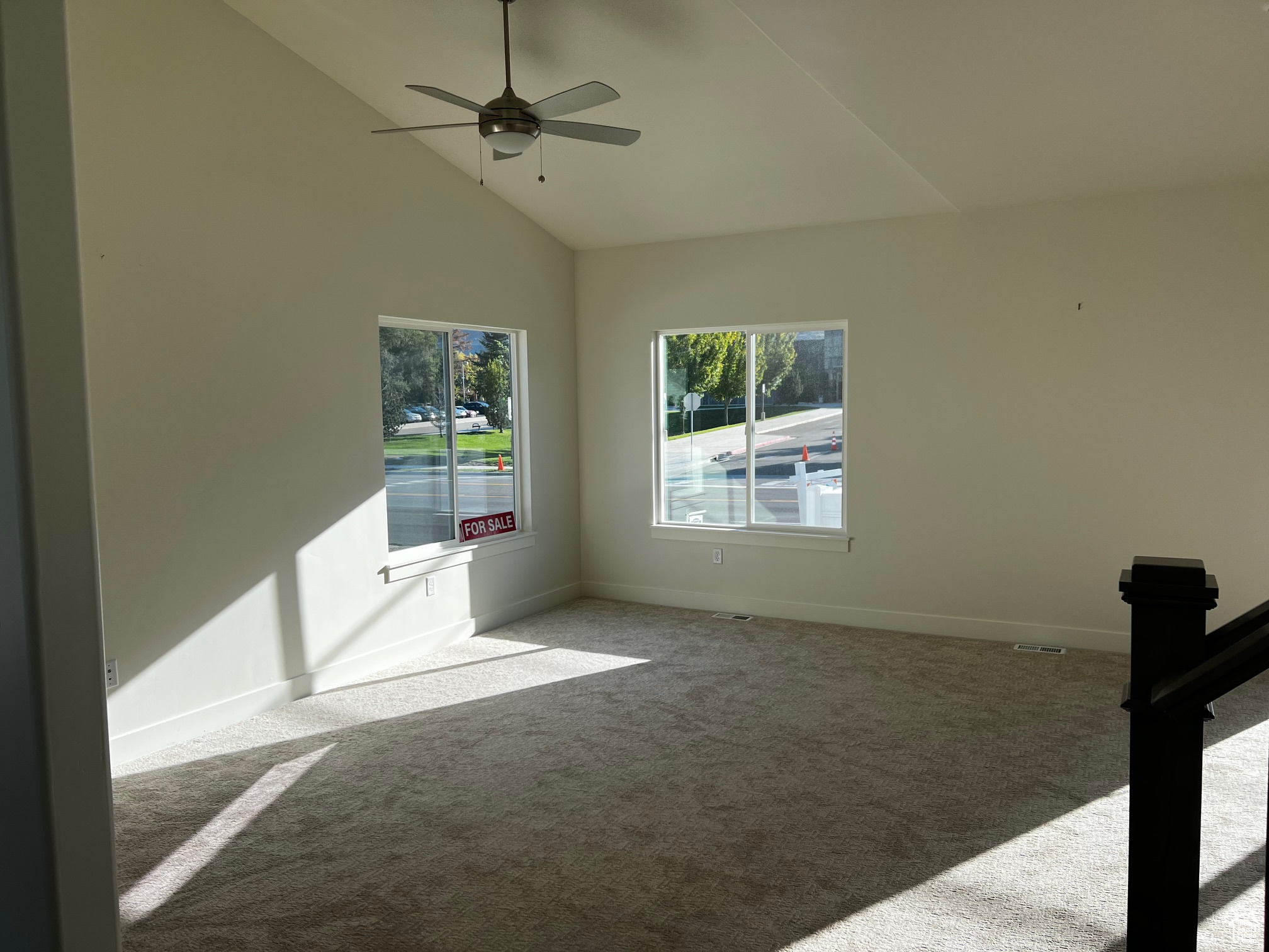 Carpeted empty room with high vaulted ceiling and ceiling fan