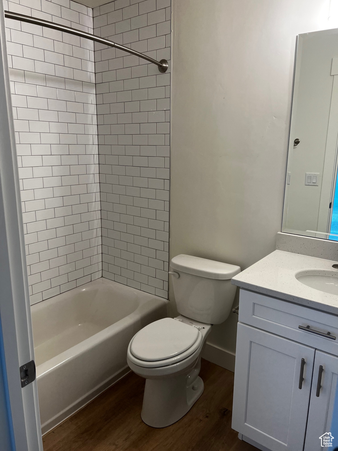 Full bathroom featuring vanity, toilet, tiled shower / bath combo, and wood-type flooring