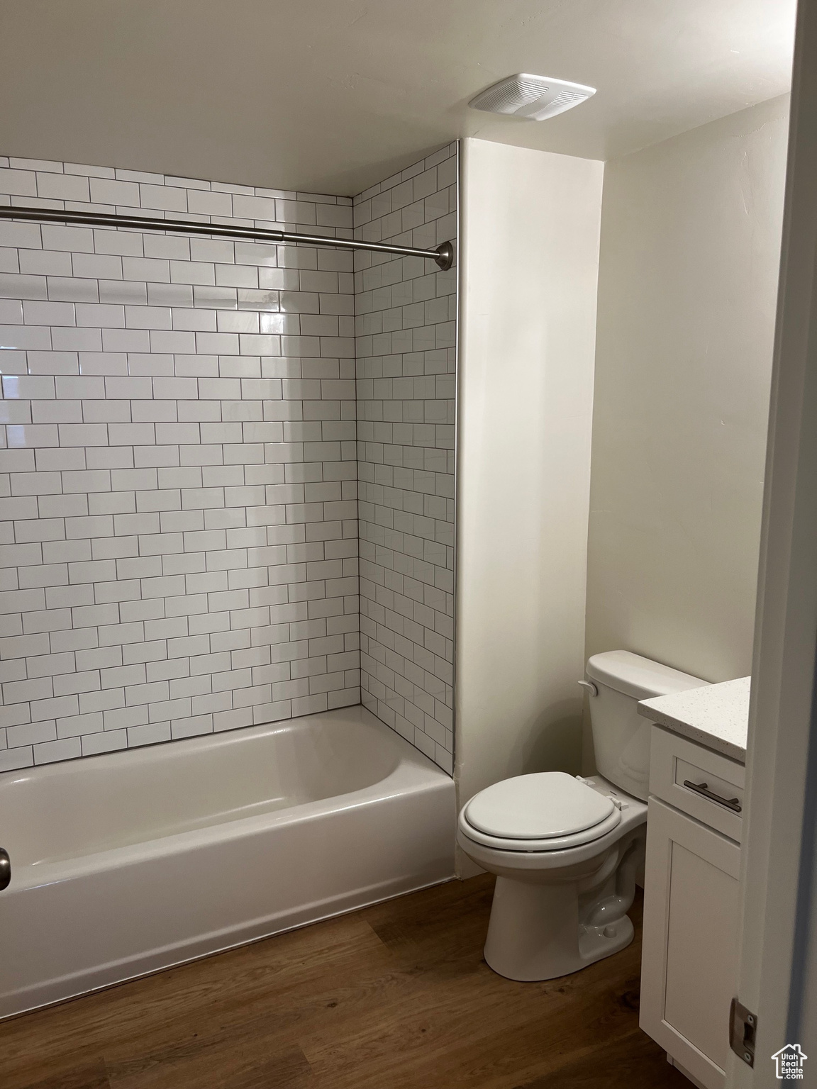 Full bathroom featuring vanity, tiled shower / bath combo, wood-type flooring, and toilet