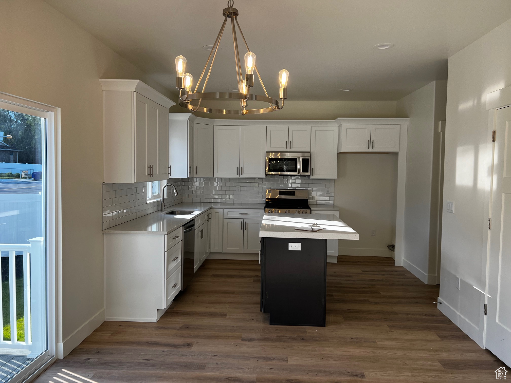 Kitchen featuring stainless steel appliances, sink, a center island, pendant lighting, and white cabinetry