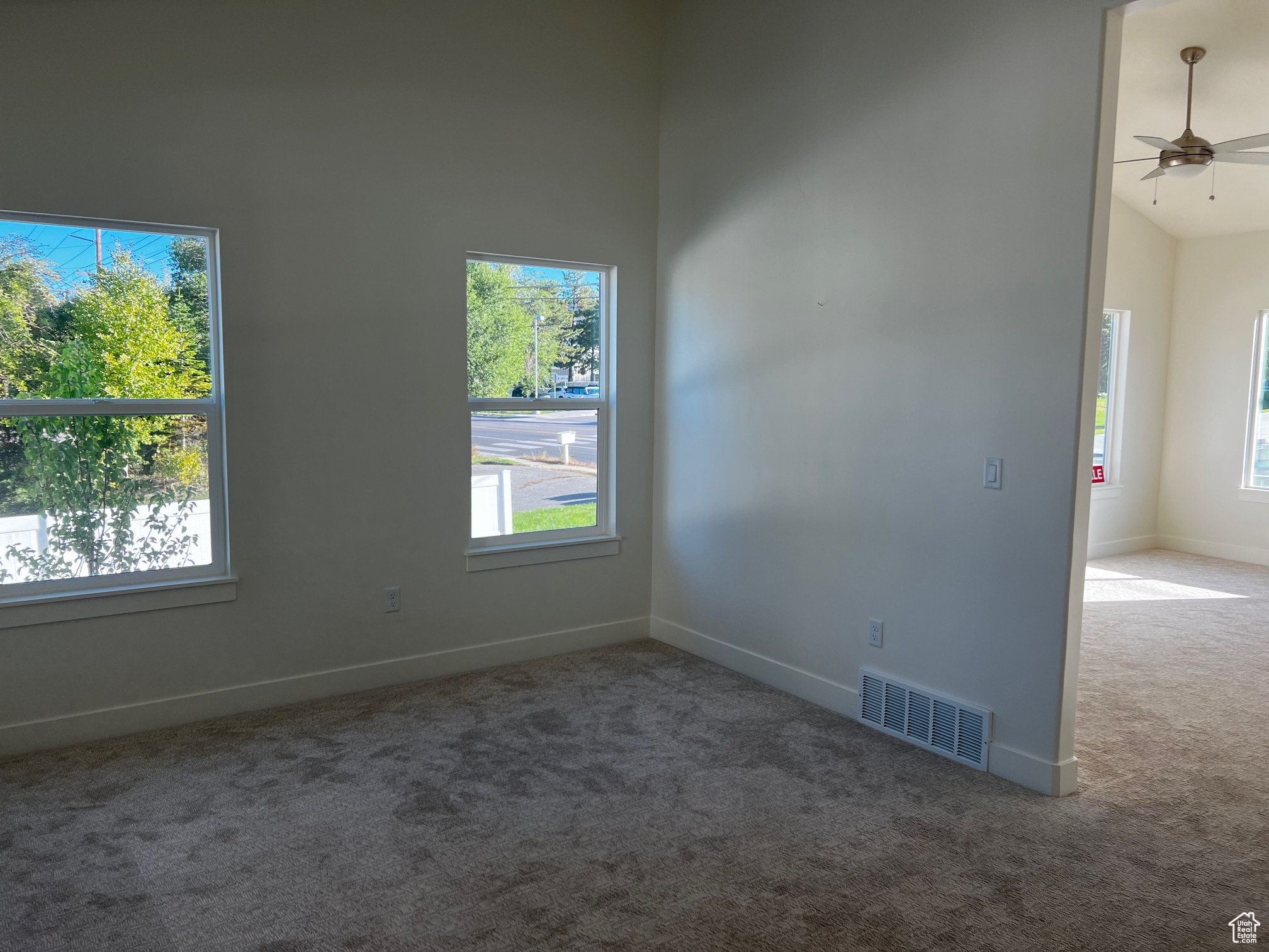 Empty room with carpet flooring, high vaulted ceiling, and ceiling fan