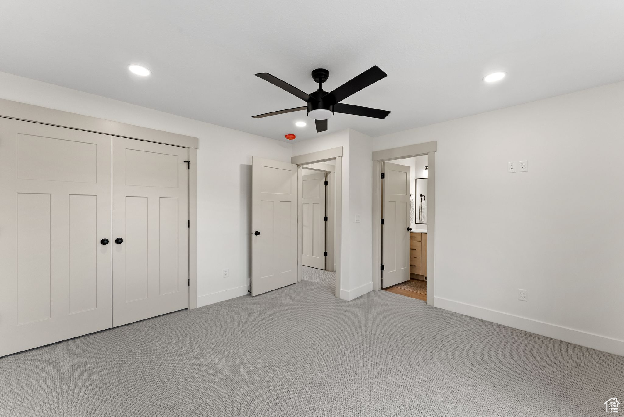 Unfurnished bedroom with ensuite bath, ceiling fan, a closet, and light colored carpet