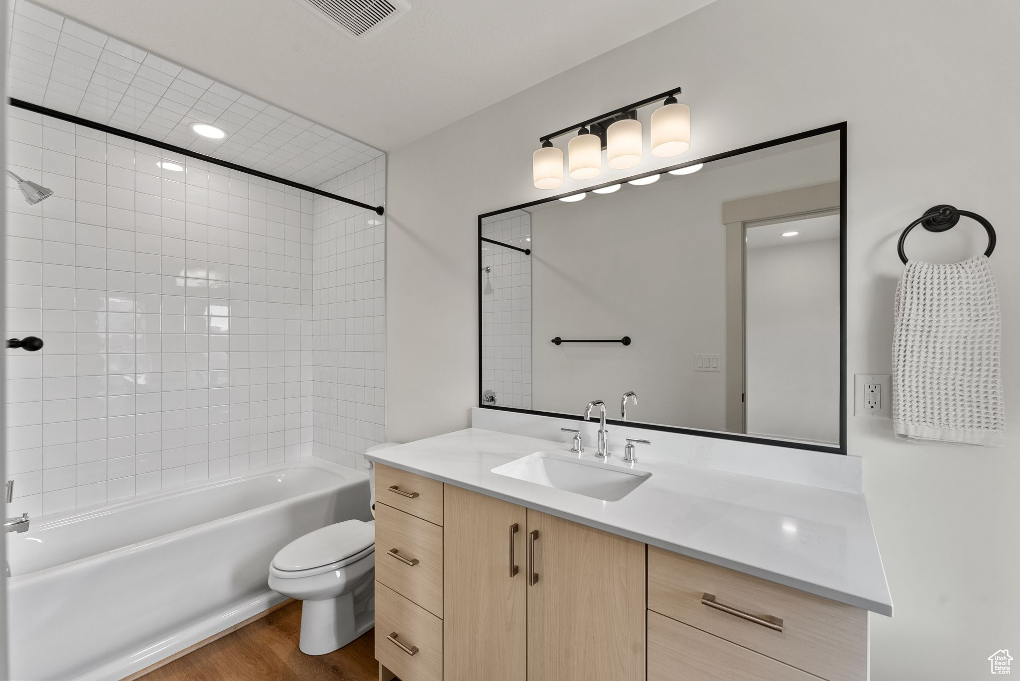 Full bathroom with vanity, hardwood / wood-style flooring, toilet, and tiled shower / bath