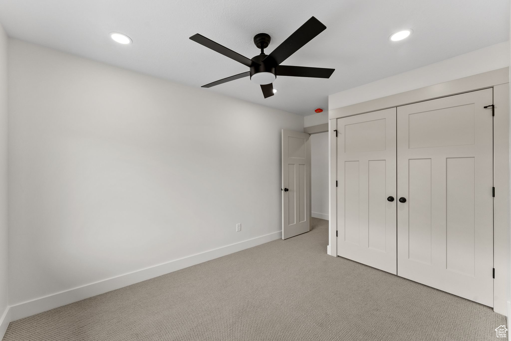 Unfurnished bedroom featuring ceiling fan, light carpet, and a closet