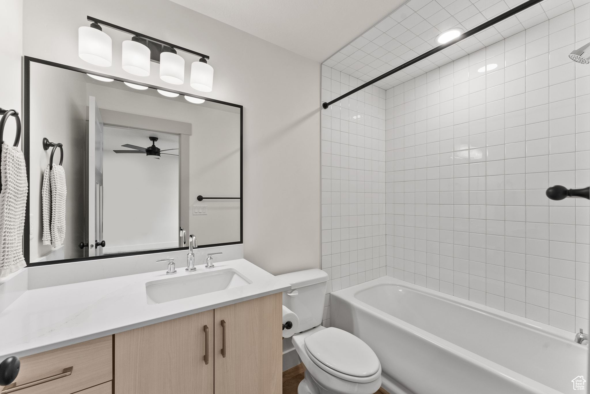 Full bathroom with vanity, ceiling fan, toilet, and tiled shower / bath combo