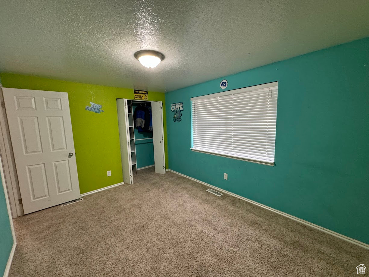 Unfurnished bedroom with a closet, carpet flooring, baseboards, and visible vents