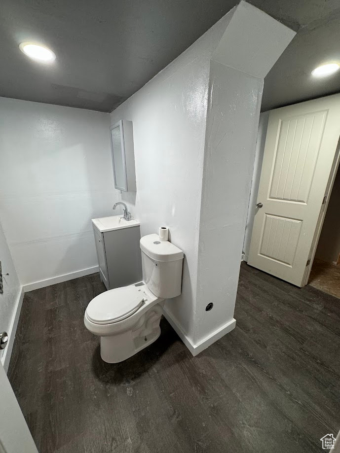 Bathroom with vanity, toilet, wood finished floors, and baseboards