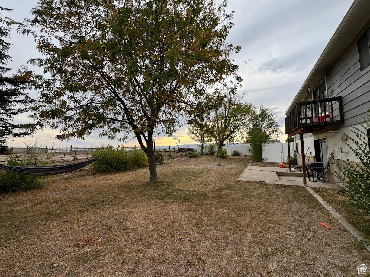 View of yard with a fenced backyard, a balcony, and a patio