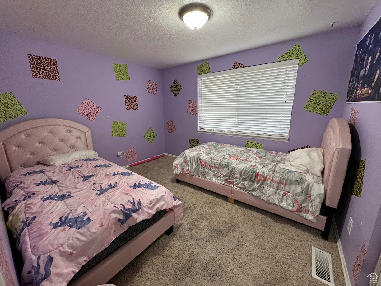 Bedroom featuring baseboards, visible vents, carpet floors, and a textured ceiling