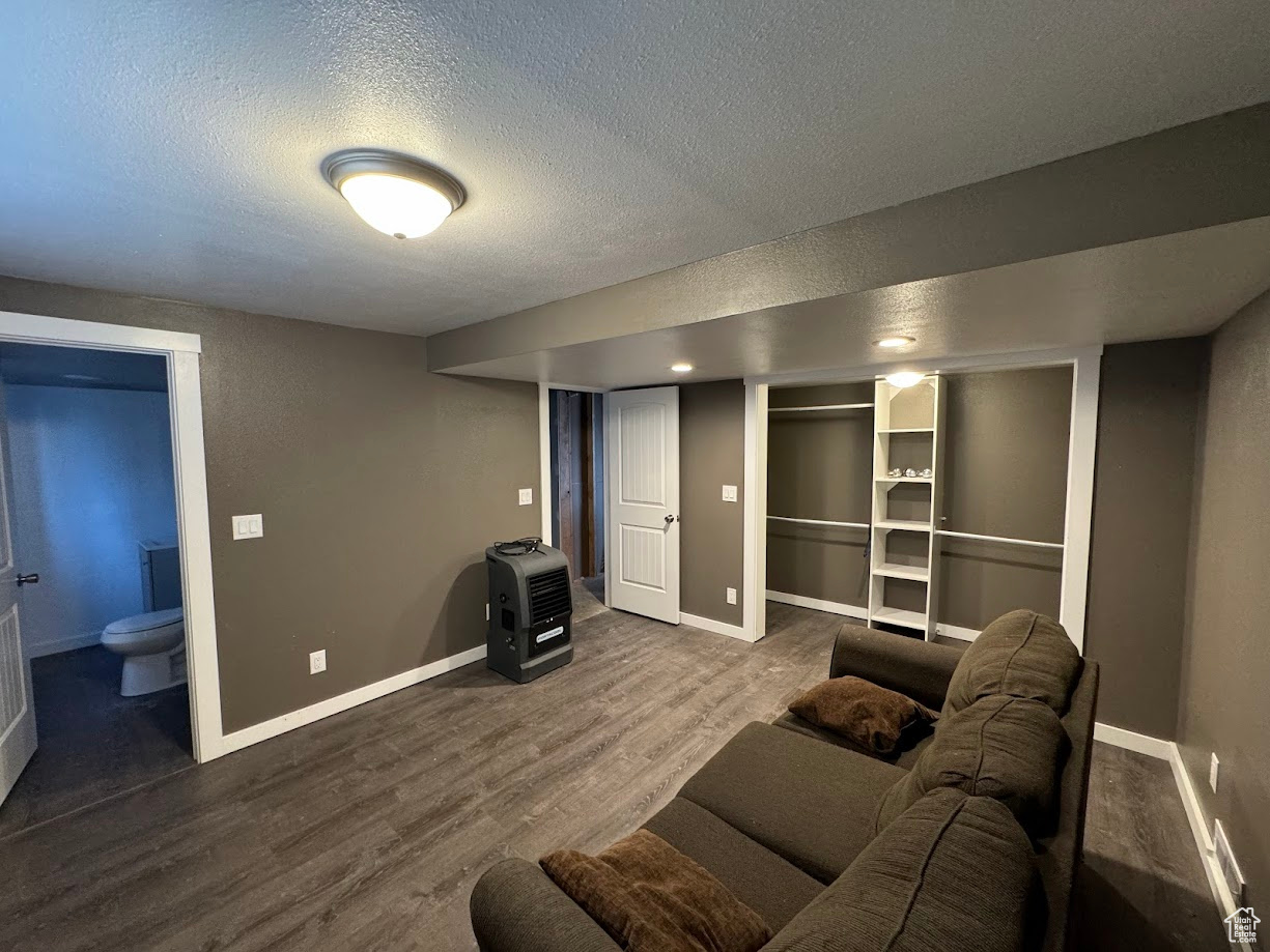 Living area featuring a textured ceiling, baseboards, and wood finished floors