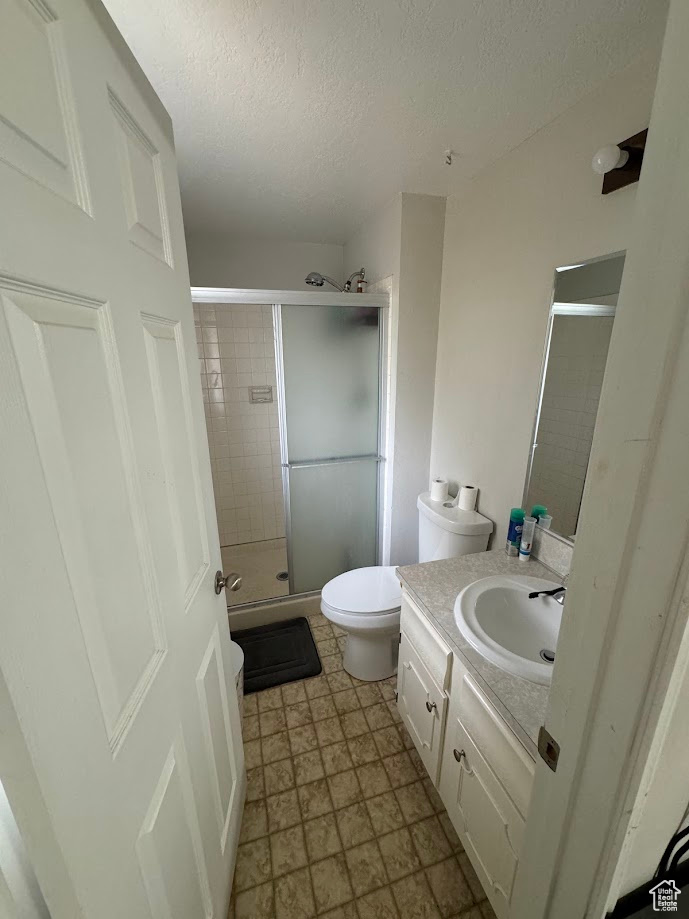 Bathroom featuring vanity, a shower stall, toilet, and a textured ceiling