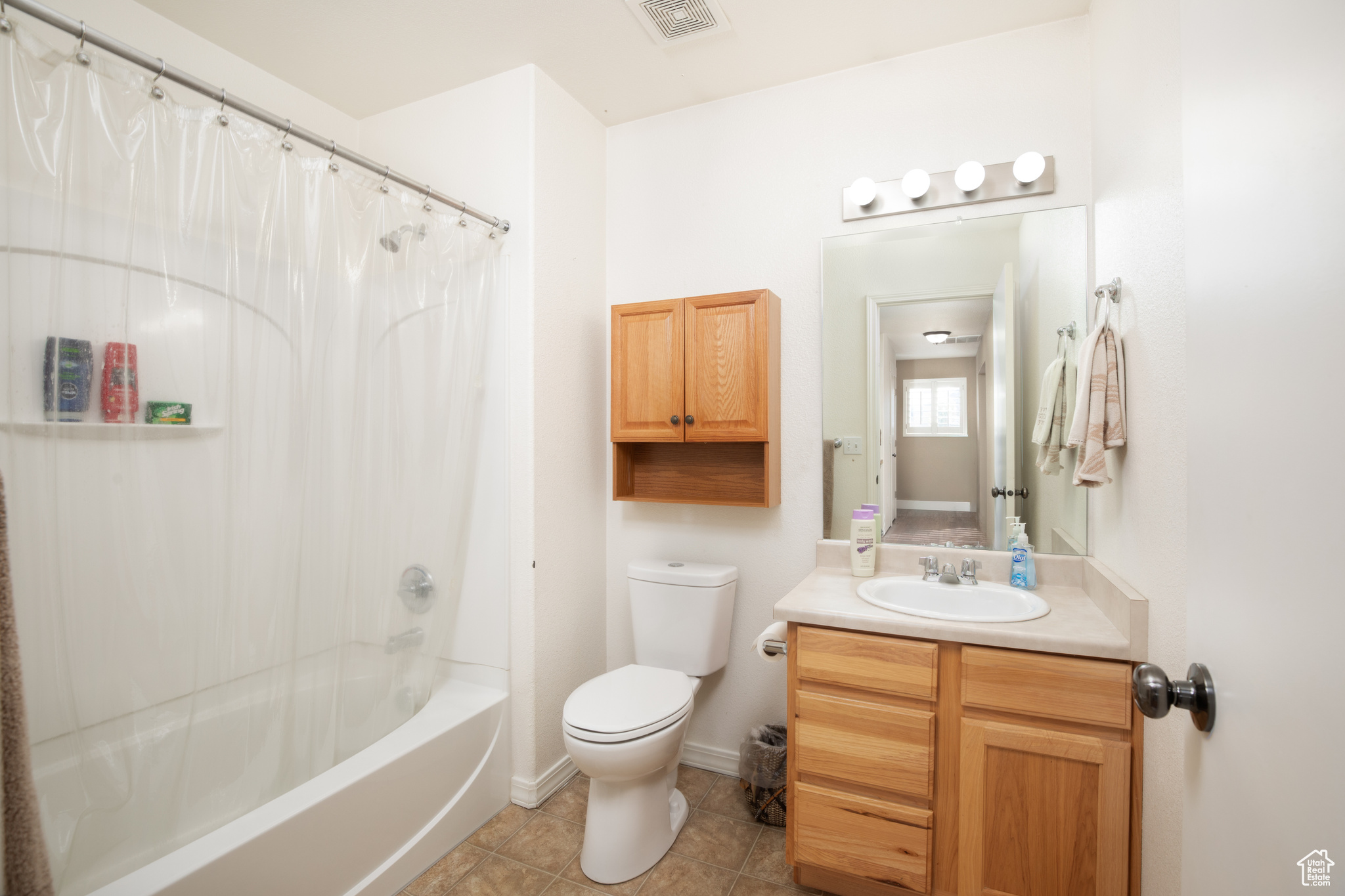 Full bathroom with toilet, vanity, shower / bath combination with curtain, and tile patterned floors