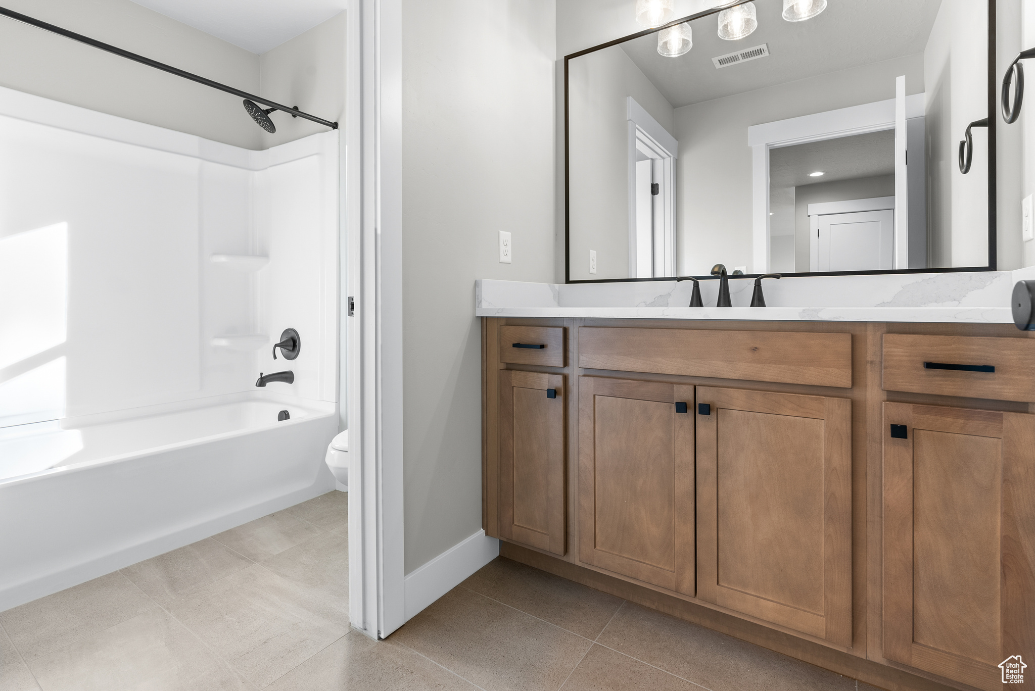 Full bathroom with tile patterned flooring, vanity, toilet, and washtub / shower combination