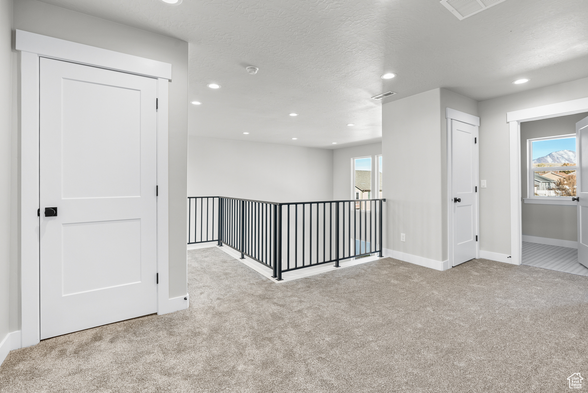 Hallway featuring light carpet and a textured ceiling