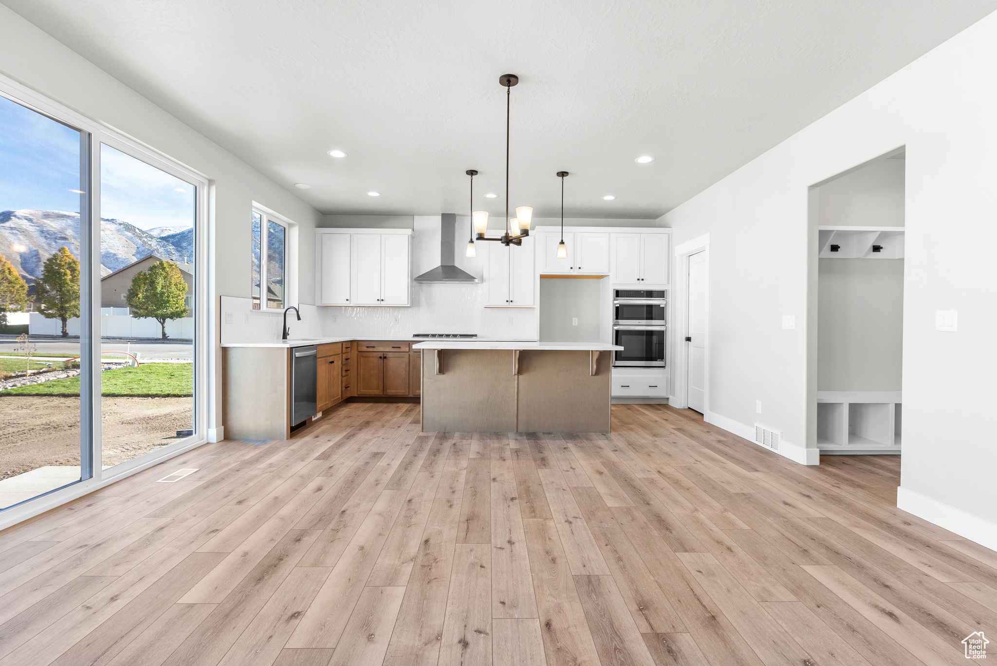 Kitchen with a center island, white cabinets, hanging light fixtures, and appliances with stainless steel finishes