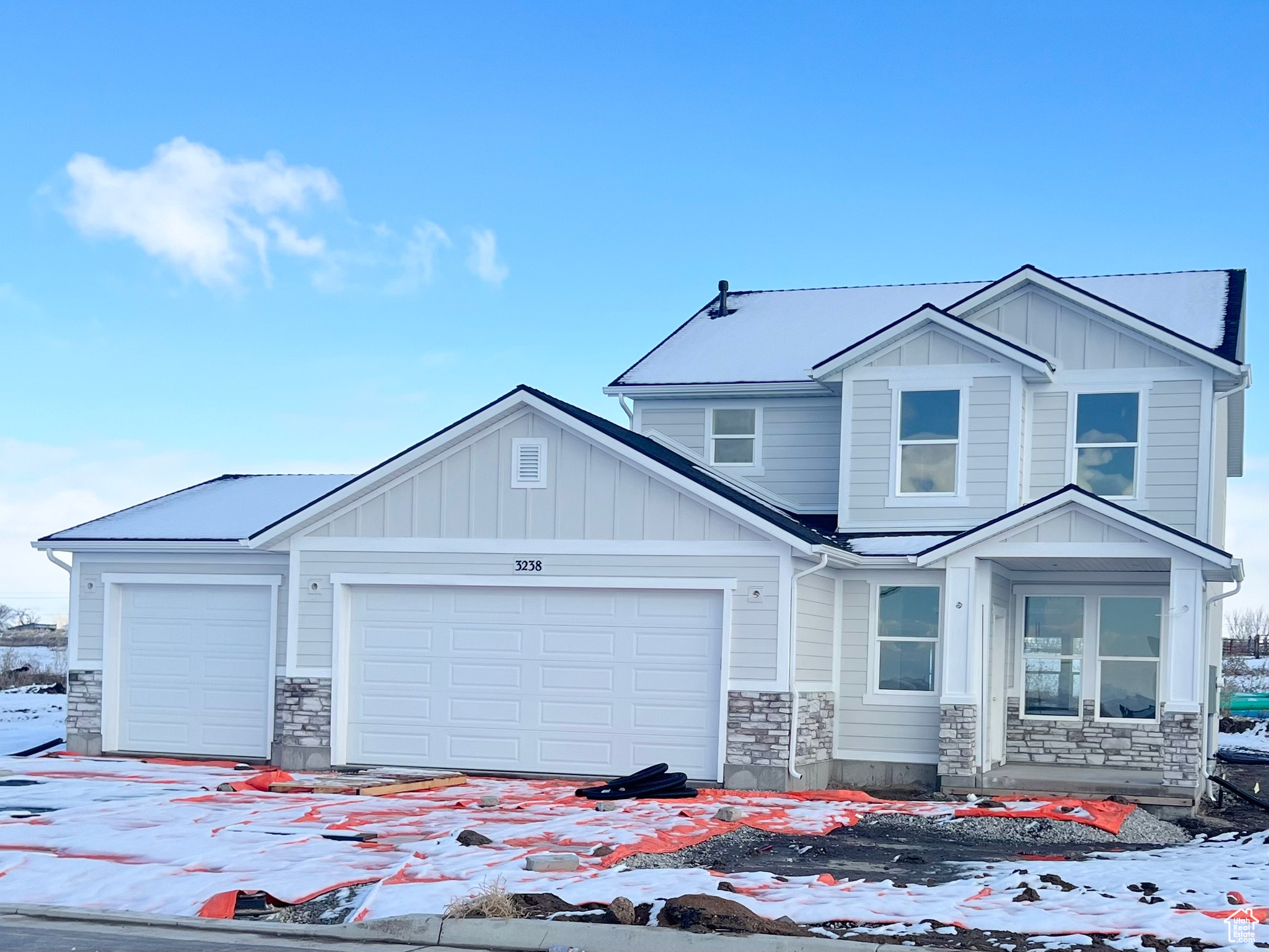 View of front of house with board and batten siding, stone siding, and an attached garage