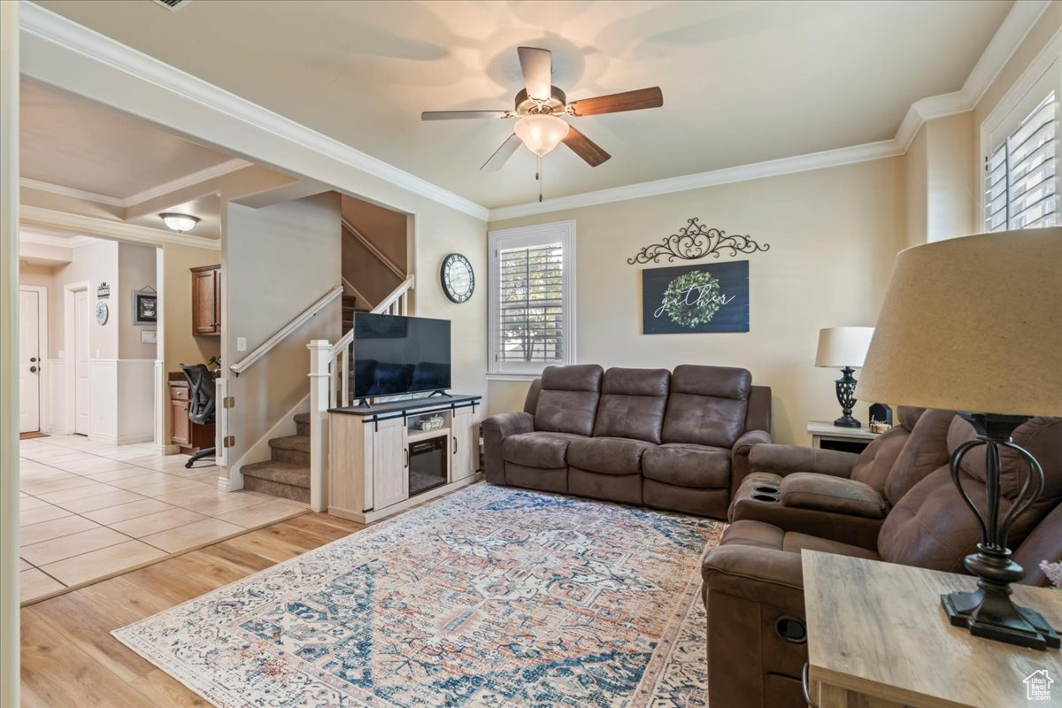 Living room featuring crown molding, light wood vinyl flooring, and ceiling fan