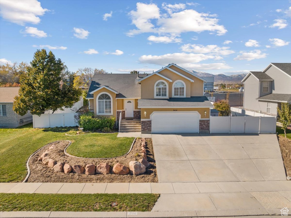 View of front of property featuring a garage, a front lawn, and a mountain view