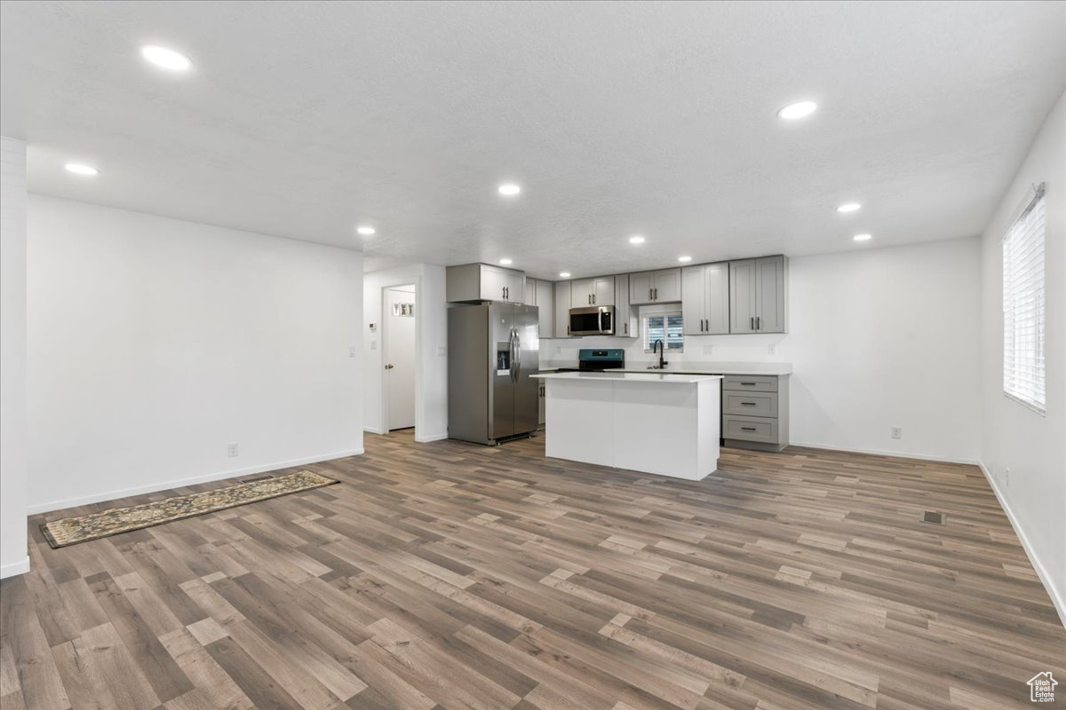 Kitchen with stainless steel appliances, hardwood / wood-style flooring, sink, a center island, and gray cabinetry