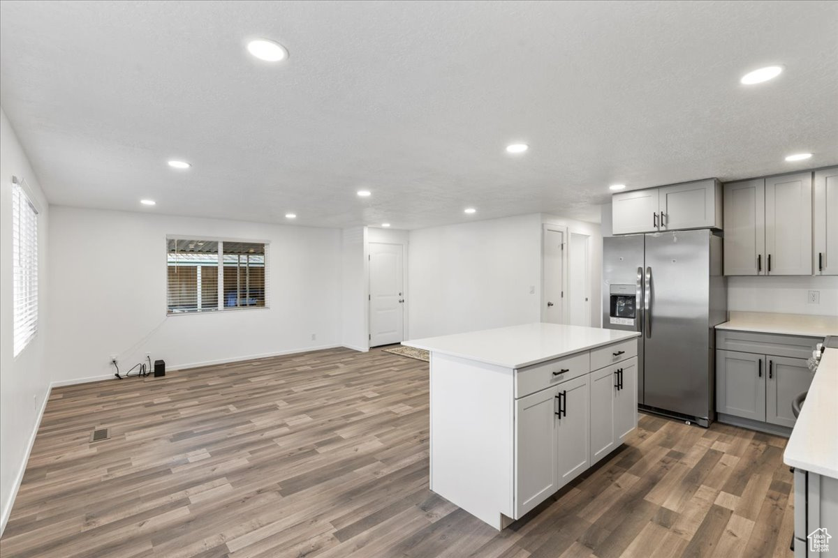 Kitchen featuring gray cabinets, a kitchen island, stainless steel refrigerator with ice dispenser, and hardwood / wood-style floors