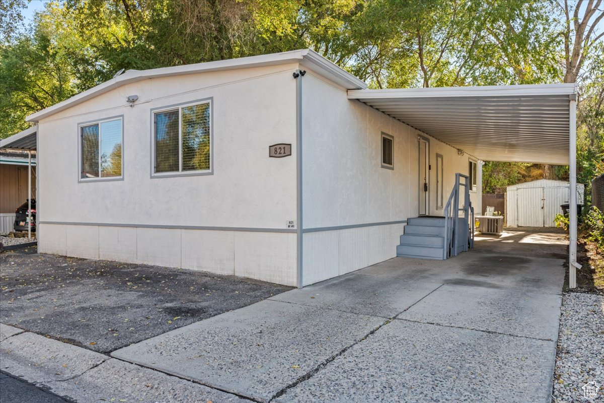 View of side of home featuring a carport and a shed