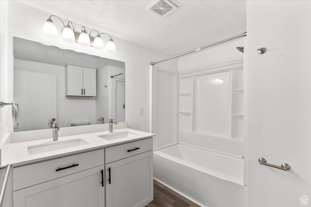 Bathroom with hardwood / wood-style floors, vanity, a textured ceiling, and shower / bathtub combination