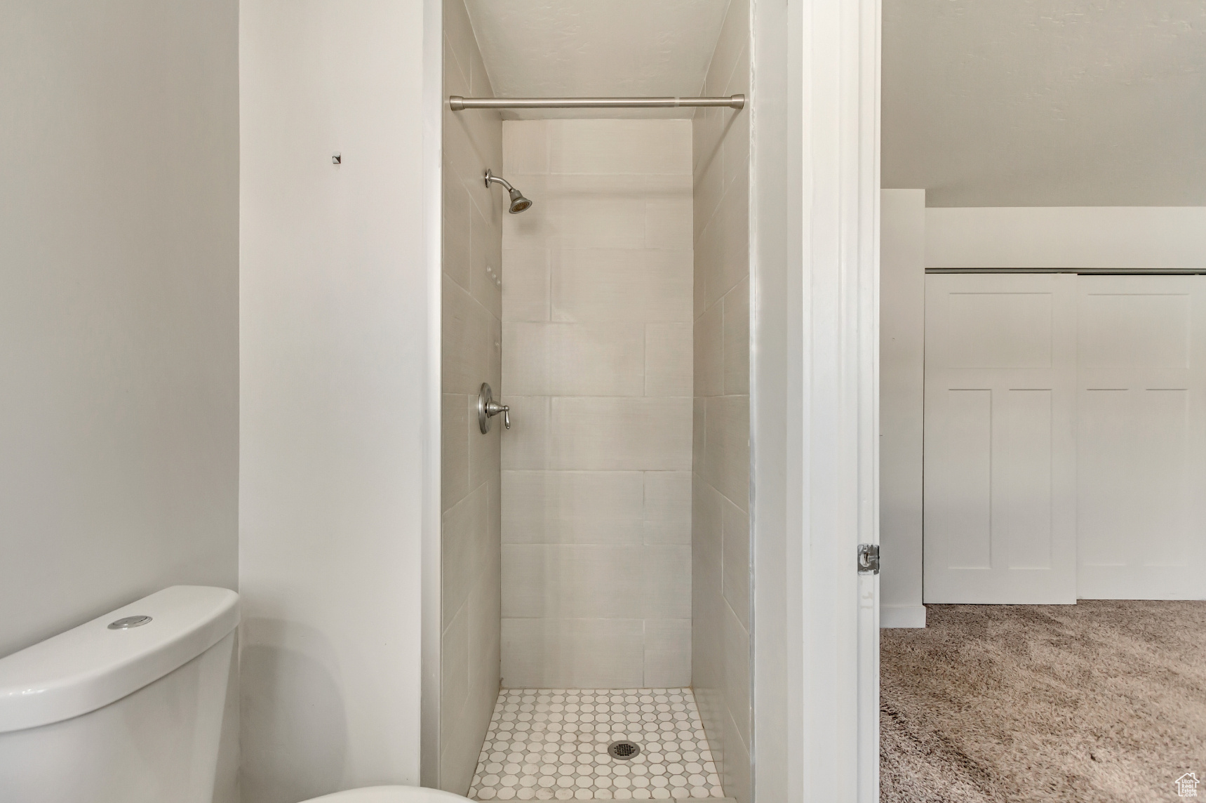 Bathroom featuring tiled shower and toilet