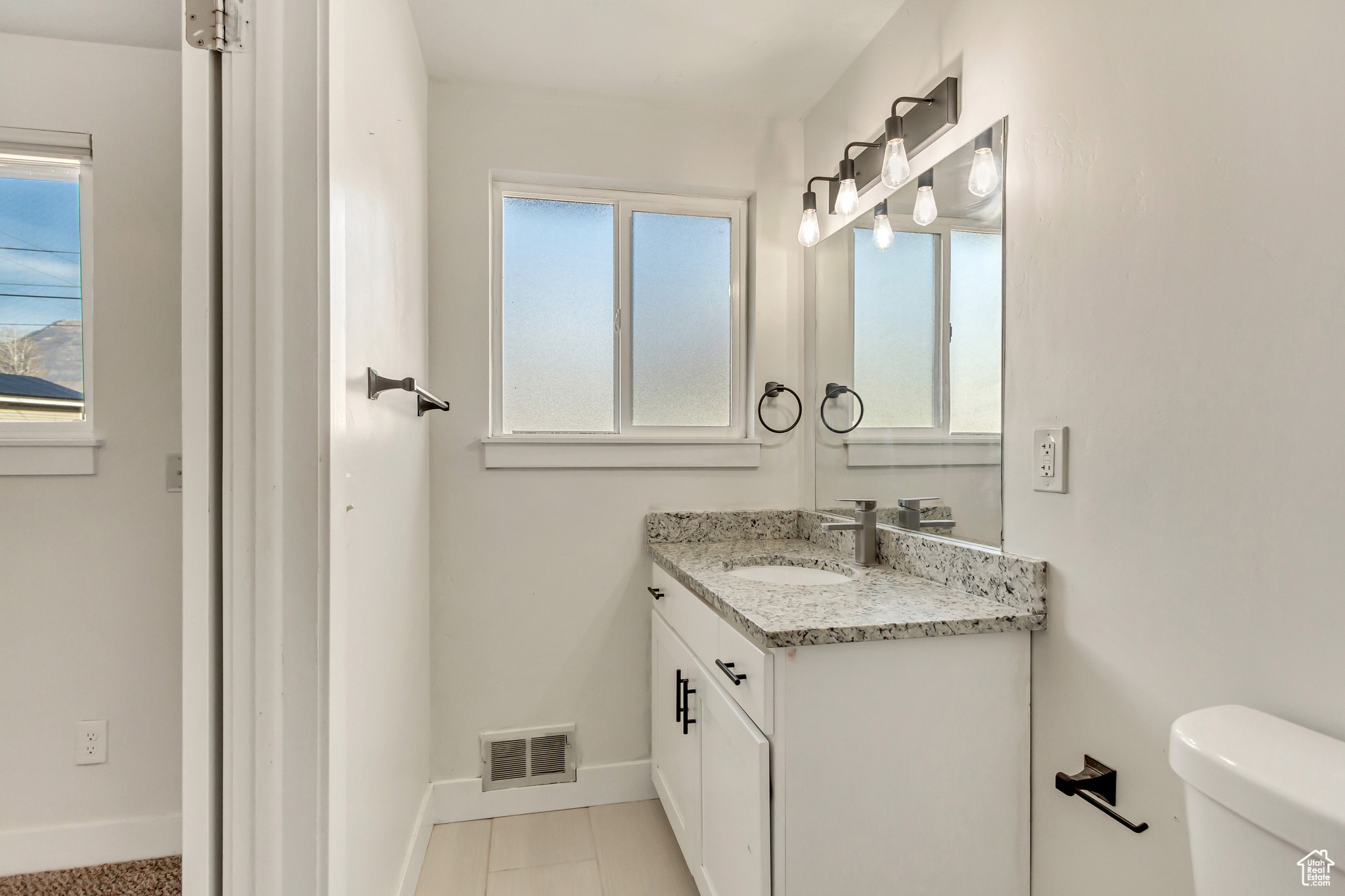 Bathroom featuring tile patterned flooring, vanity, and toilet